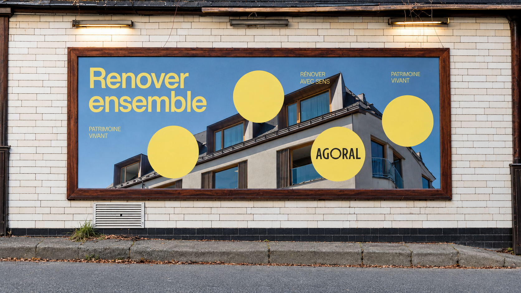 Affiche AGORAL « Rénover avec sens » fixée sur un mur en briques blanches